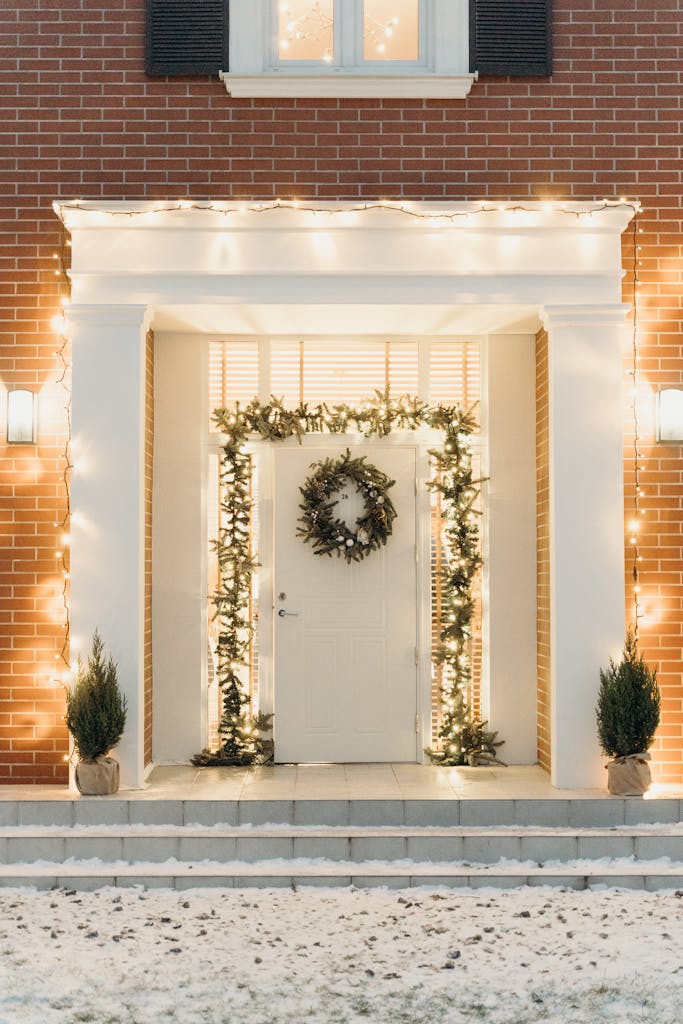 A beautifully decorated doorway with holiday lights and a wreath during winter.